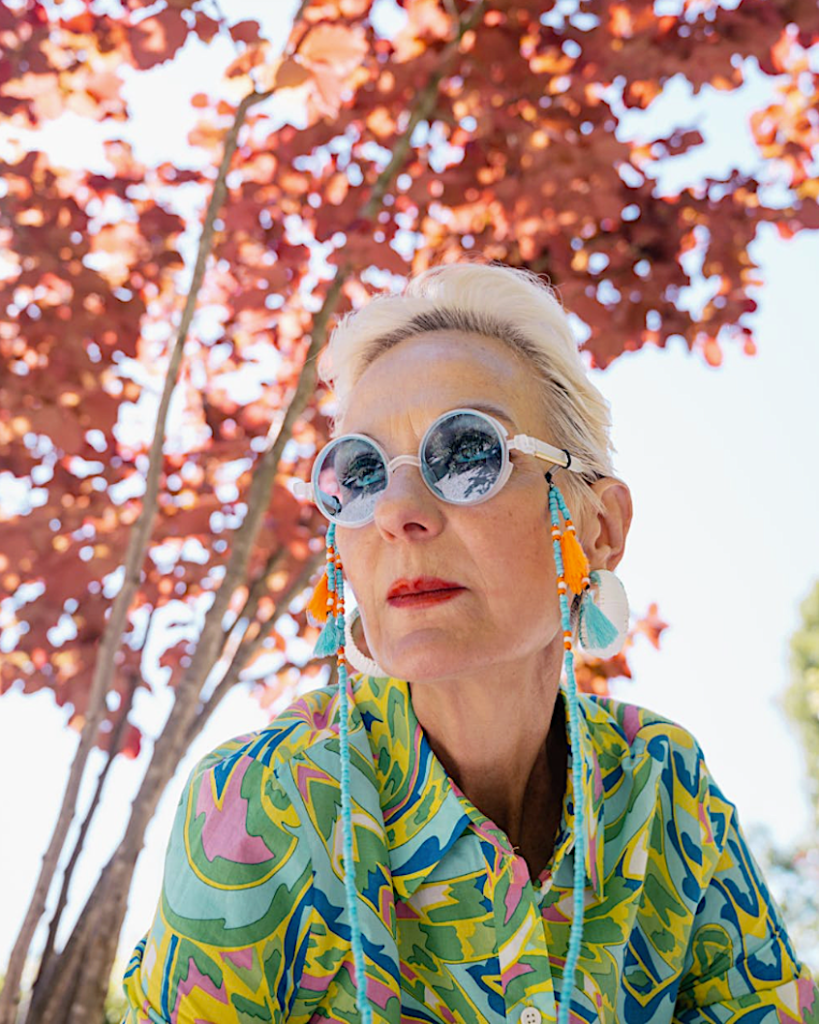 A woman posing in front of a red-leafed tree